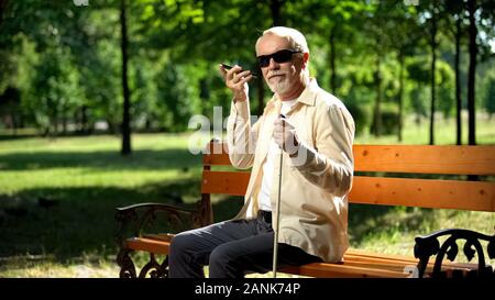 Visually impaired old man using voice control app in smartphone, innovations Stock Photo
