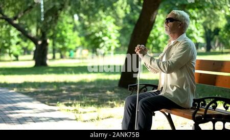 Old blind man sitting on bench, thinking about life injustice feeling frustrated Stock Photo