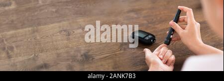 Cropped Image Of Young Woman Using Glucometer To Check Blood Sugar Level At Home Stock Photo