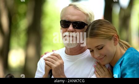 Supportive nurse hugging elderly blind patient, psychological help, rehab center Stock Photo