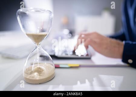 Hourglass In Front Of Businessperson Calculating Invoice Stock Photo