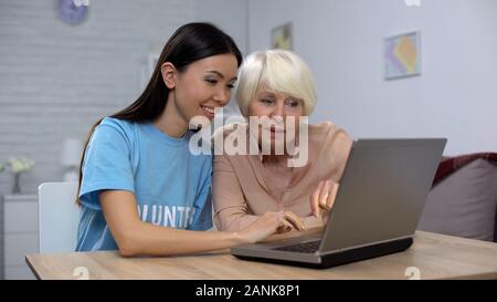 Social activist and senior woman watching photos on laptop, spending free time Stock Photo