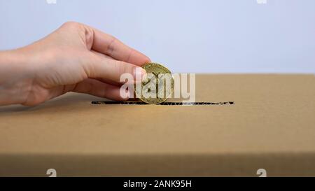 Hand putting bitcoin in carton box, online donation service, internet payment Stock Photo