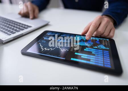 Close-up Of A Businesswoman's Hand Analyzing Graph On Digital Laptop At Workplace Stock Photo