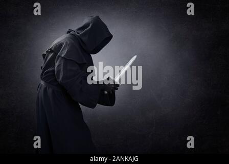 Hooded man with dagger in the dark Stock Photo