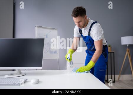 Portrait Of Happy Young Maid Cleaning Glass Table In Office Stock Photo