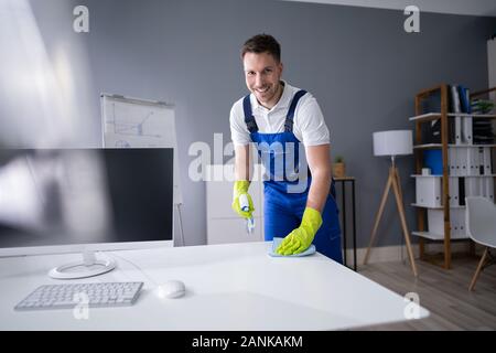 Portrait Of Happy Young Maid Cleaning Glass Table In Office Stock Photo