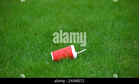 Empty paper cup lying on grass, food waste recycling, environmental protection Stock Photo