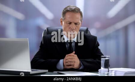 Stressed boss sitting at office desk, feeling nervous because of meeting result Stock Photo