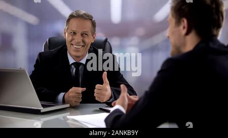 Friendly boss showing thumbs-up to candidate on interview, supporting employee Stock Photo