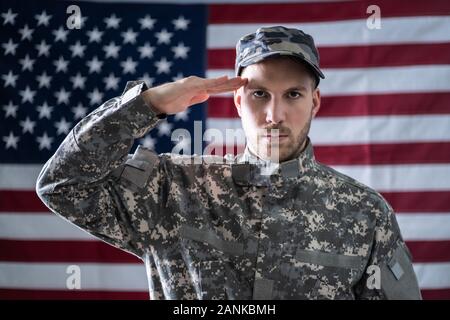 Portrait Of Army Soldier Saluting In Front Of American Flag Stock Photo