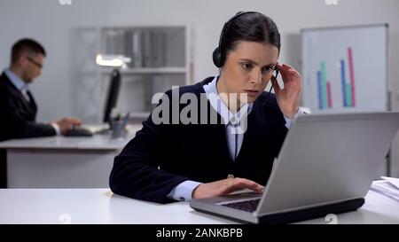 Call center manager in headset checking data on laptop, customer support Stock Photo