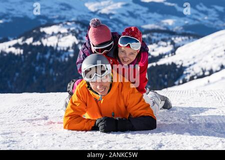 Portrait Of A Happy Family Lying Stacked On Top Of Each Other In Snow Stock Photo