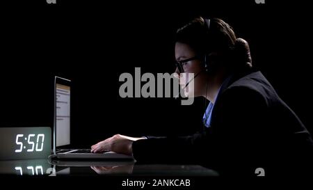 Responsible female call-center employee in headphones working at night shift Stock Photo