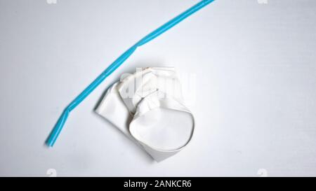 Crumpled coffee cup and plastic straw lying on white background, recycling Stock Photo