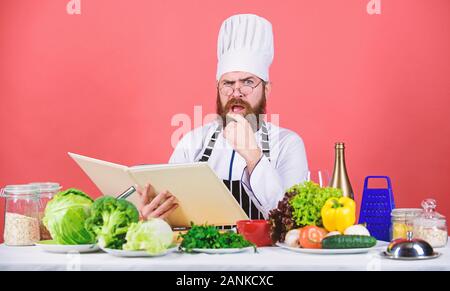 Bearded man cook in kitchen, culinary. Healthy food cooking. Dieting and organic food, vitamin. We detest vegetables. Vegetarian. Mature chef with beard. Chef man in hat. Secret taste recipe. Stock Photo