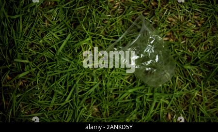 Crumpled plastic cup thrown on lawn, environmental pollution problem, recycling Stock Photo