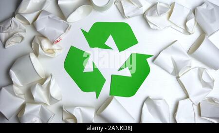 Crumpled disposable paper cups lying around recycling sign, save nature concept Stock Photo