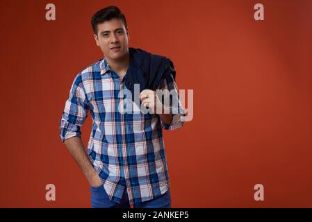 Young man with jacket on shoulder isolated on orange color studio background Stock Photo