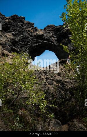 Icelandic lava rock formations and famous hole at Dimmuborgier black fortresses near lake myvatn. Shot on sunny day with blue sky and a few clouds in Stock Photo