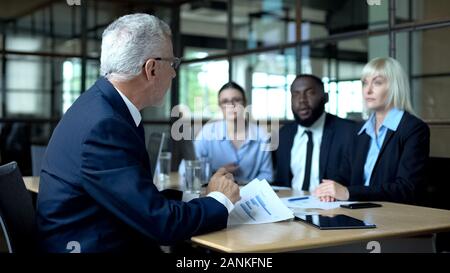 Serious director looking at company employees, discussing business strategy Stock Photo