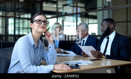 Female company employee dreaming of vacation in office, smiling thoughtfully Stock Photo