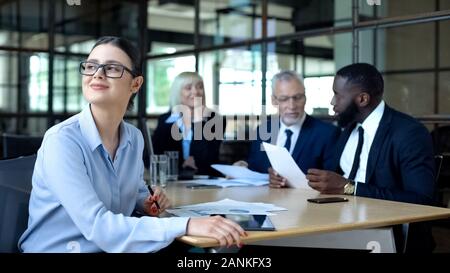 Joyful business woman dreaming during office meeting sitting at table, work Stock Photo