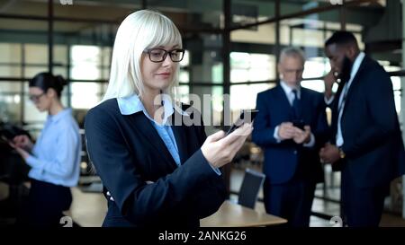 Smiling female manager reading email on smartphone, using business news app Stock Photo
