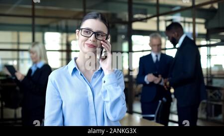 Smiling business woman talking on phone during work break, mobile conversation Stock Photo