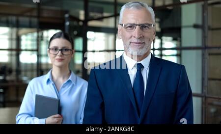 Smiling male director and female secretary looking camera, office work, business Stock Photo