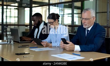 Multiracial group of office employees working smartphone, tablet and laptop Stock Photo