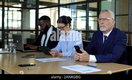 Company employees using smartphone tablet laptop, modern business technologies Stock Photo