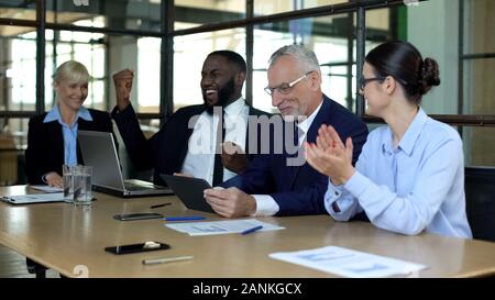 Multiracial company employees celebrating good news in office, successful deal Stock Photo