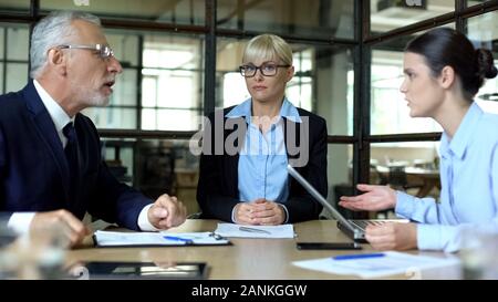 Business woman listening to emotional colleagues arguing in office, conflict Stock Photo