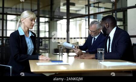 Male colleagues ignoring female partner discussing business issues, woman rights Stock Photo