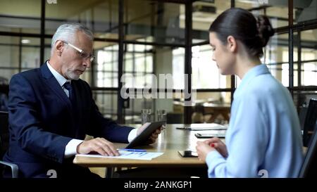 Aged businessman scrolling company app on tablet unhappy with work results Stock Photo