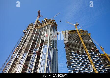 DUBAI, UNITED ARAB EMIRATES - NOVEMBER 19, 2019: Skyscrapers under construction with cranes, low angle view in a sunny day, clear blue sky in Dubai Stock Photo