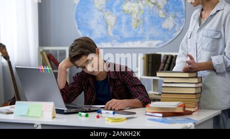 Strict mother with books scolding her son while he playing videogame at ...