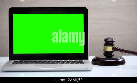 Green screen laptop on table, gavel standing on sound block, fine payment app Stock Photo