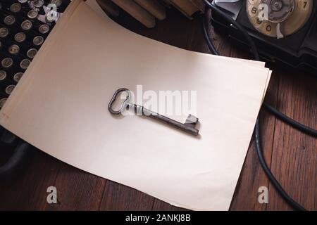 Old retro vintage typewriter and blank sheet of paper with key on wooden table Old retro vintage typewriter and blank sheet of paper with key on wooden table
