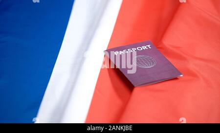 Female hand putting international red passport on french flag, citizenship Stock Photo