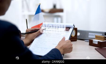 Embassy employee checking visa application office, french flag, migration Stock Photo