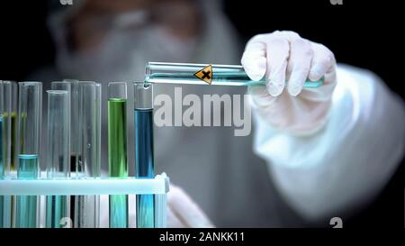 Lab assistant adding liquid from test tube with cross symbol, illegal research Stock Photo