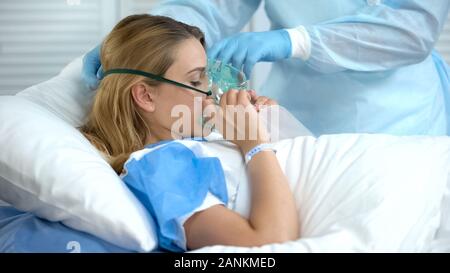 Nurse wearing female patient oxygen mask, preparation before surgery, hospital Stock Photo