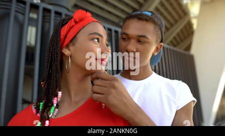 Multiracial couple looking at each other, boy holding girl chin, before kiss