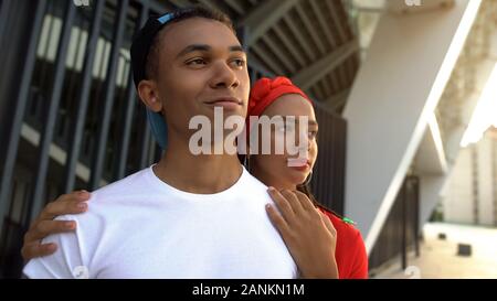 Girl hugs boyfriend looking self-confidently ahead, importance of female support Stock Photo