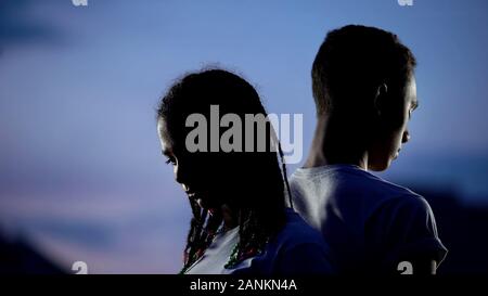 Upset teenagers standing back to back, forced separation, break-up concept Stock Photo