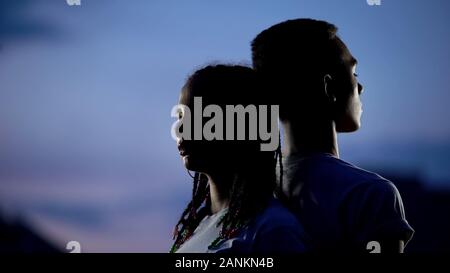 Couple standing to each other back in darkness, confronting problems together Stock Photo