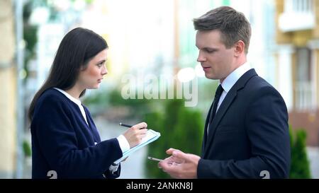 Female secretary recording in notebook male boss orders, personal assistant Stock Photo