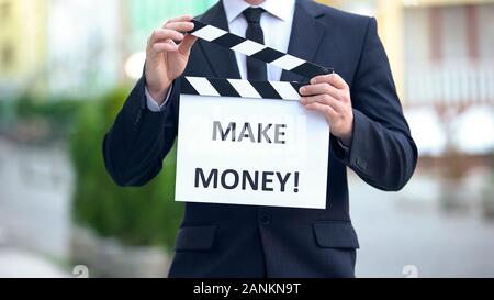 Make money phrase on clapperboard in hands of successful businessman, workshop Stock Photo